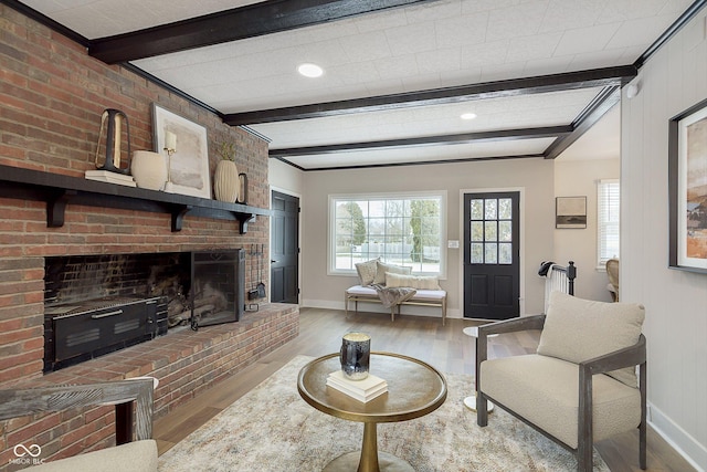 living room with hardwood / wood-style flooring, a brick fireplace, and beamed ceiling