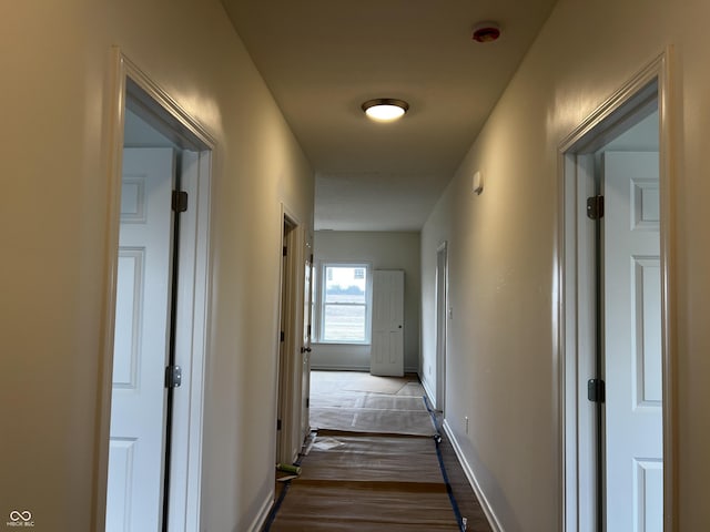 corridor with baseboards and wood finished floors