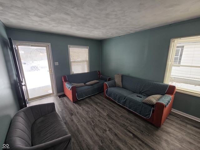 living room featuring a textured ceiling, dark hardwood / wood-style flooring, and a healthy amount of sunlight