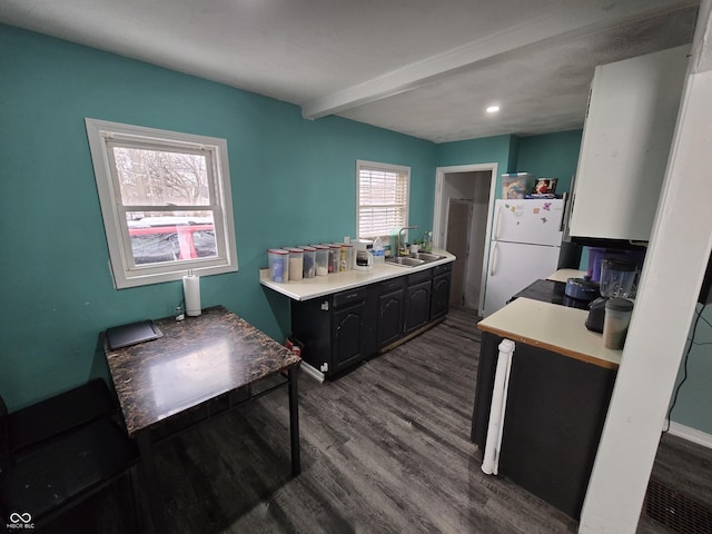 kitchen featuring beam ceiling, dark wood-type flooring, sink, and white fridge