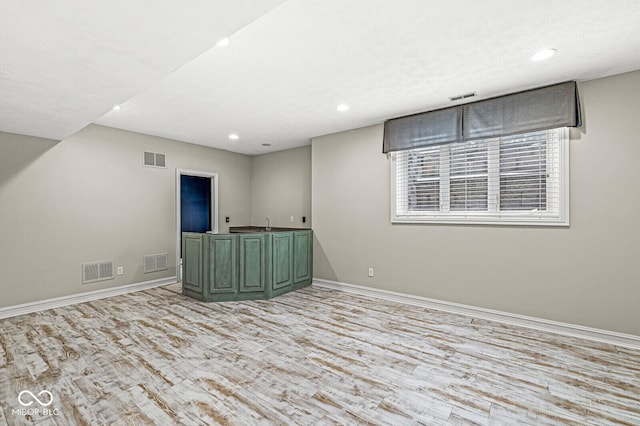 spare room with bar area and light wood-type flooring