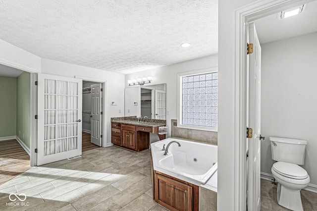 bathroom with vanity, a tub, a textured ceiling, and toilet