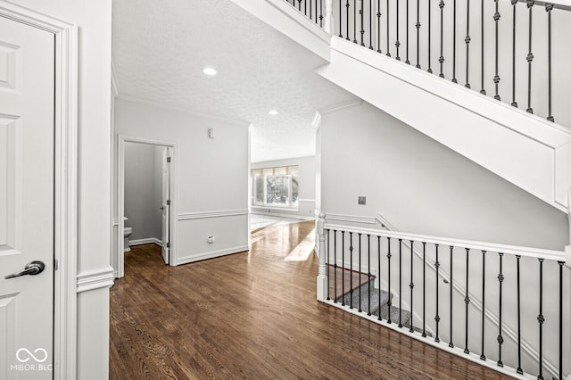 hall featuring dark wood-type flooring, ornamental molding, and a textured ceiling