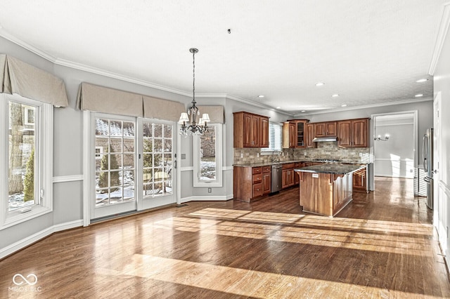 kitchen with a kitchen island, appliances with stainless steel finishes, tasteful backsplash, a chandelier, and hanging light fixtures