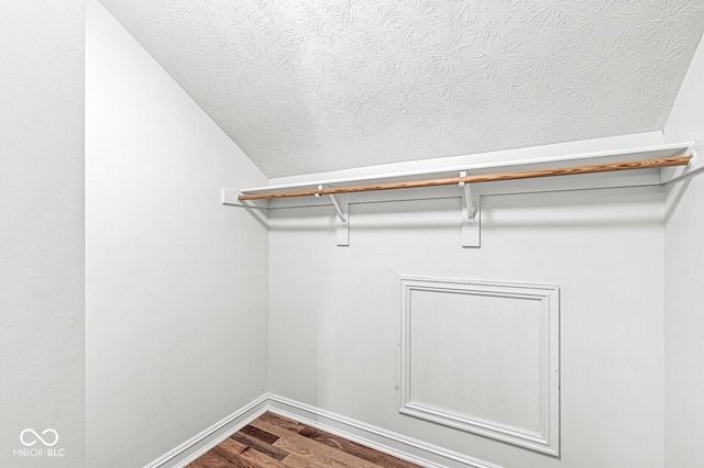 walk in closet with hardwood / wood-style flooring and vaulted ceiling