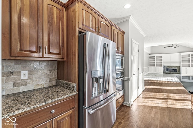 kitchen featuring appliances with stainless steel finishes, dark hardwood / wood-style floors, a fireplace, ornamental molding, and a textured ceiling