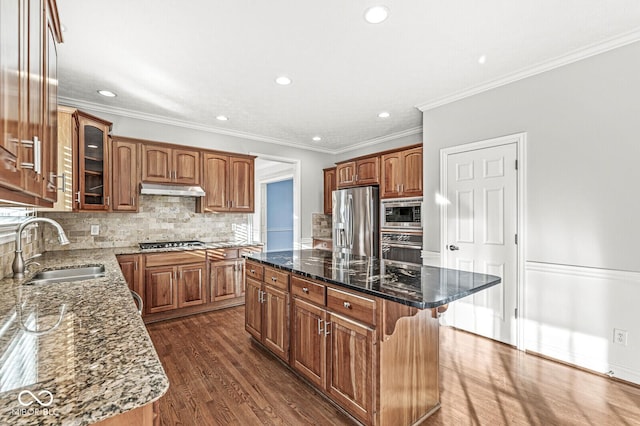 kitchen featuring sink, appliances with stainless steel finishes, dark stone countertops, a center island, and decorative backsplash