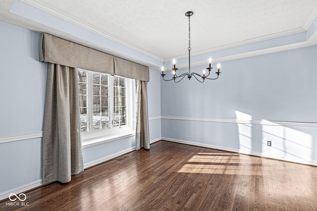 unfurnished dining area featuring a chandelier, a textured ceiling, ornamental molding, a tray ceiling, and dark hardwood / wood-style flooring