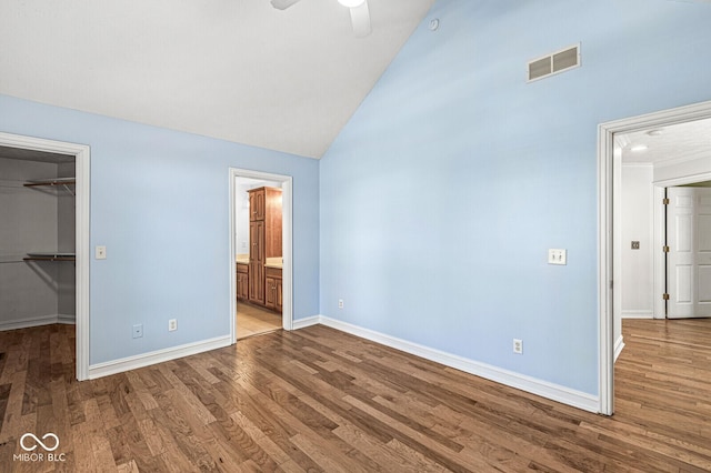 unfurnished bedroom with a closet, lofted ceiling, a spacious closet, ceiling fan, and light hardwood / wood-style flooring