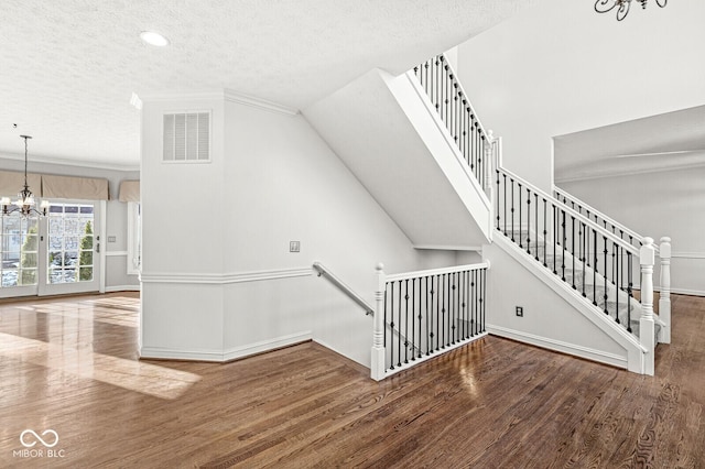 staircase with hardwood / wood-style floors, a chandelier, and a textured ceiling