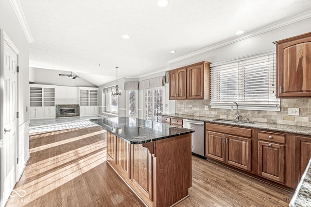 kitchen featuring sink, vaulted ceiling, dishwasher, a kitchen island, and dark stone counters