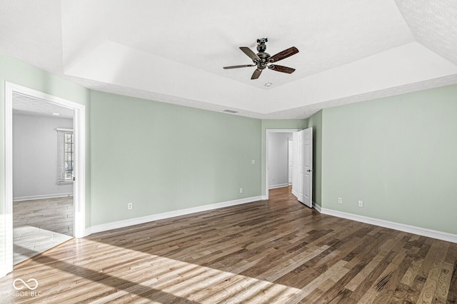 empty room featuring hardwood / wood-style floors, a raised ceiling, and ceiling fan