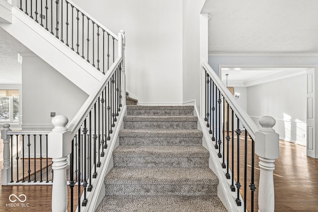 staircase with crown molding, hardwood / wood-style floors, and a chandelier