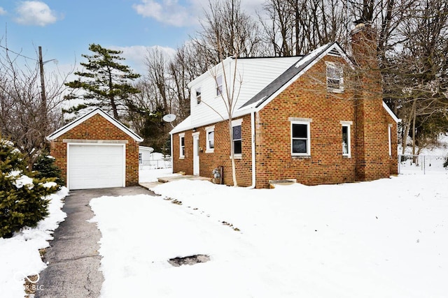 view of snowy exterior featuring a garage and an outdoor structure