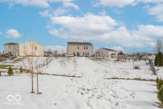 snow covered back of property featuring a playground