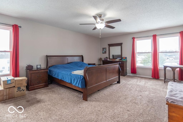 bedroom featuring ceiling fan, light colored carpet, a textured ceiling, and multiple windows