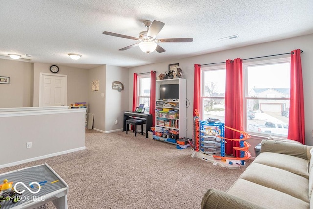 recreation room with ceiling fan, a textured ceiling, and carpet flooring