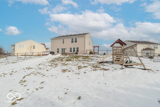 snow covered rear of property featuring a playground