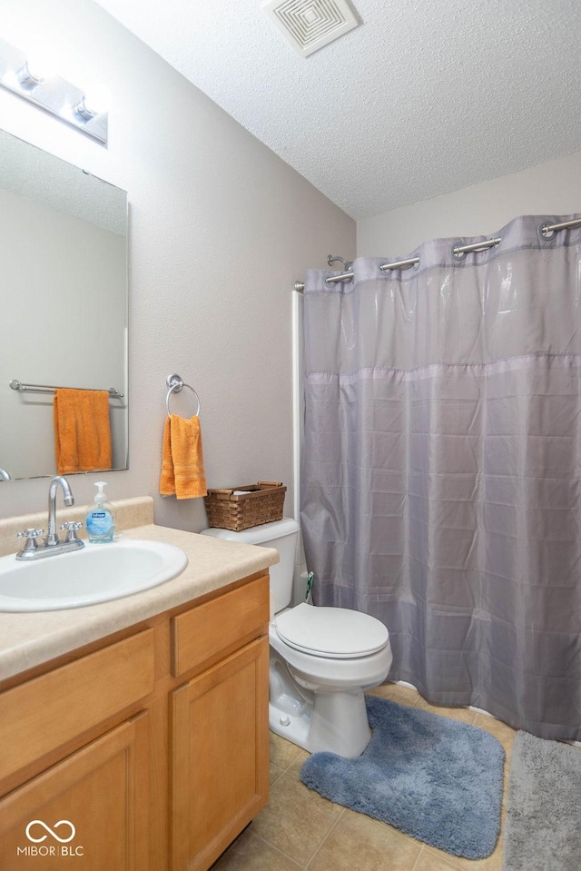 bathroom with curtained shower, a textured ceiling, tile patterned flooring, vanity, and toilet