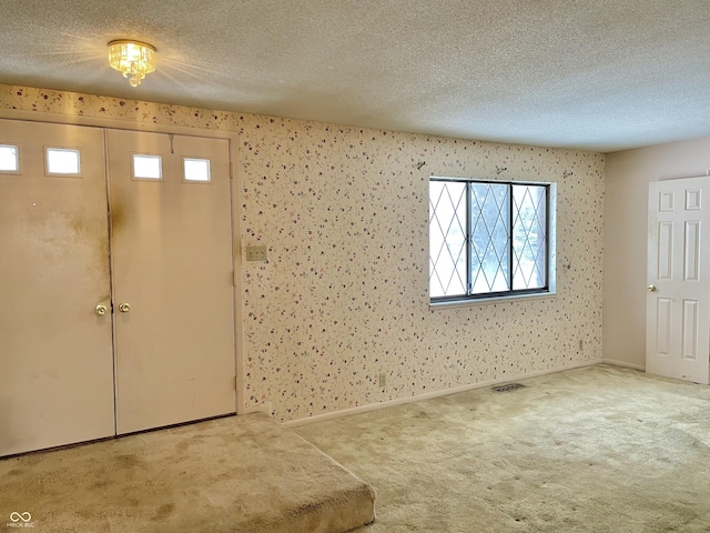 carpeted foyer with a textured ceiling