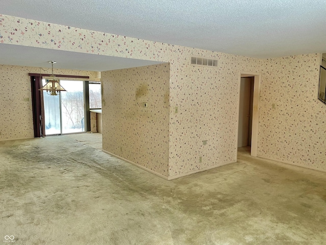 carpeted spare room featuring a notable chandelier and a textured ceiling