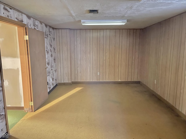 basement with a textured ceiling and wooden walls