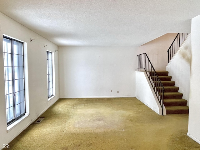 unfurnished room with carpet and a textured ceiling