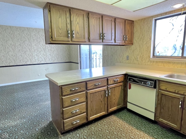 kitchen featuring white dishwasher, kitchen peninsula, and sink