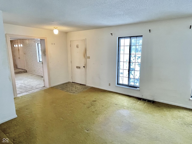 carpeted empty room with a textured ceiling