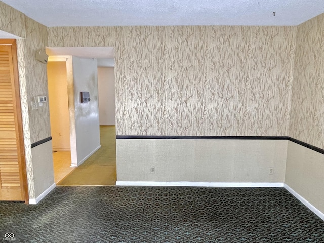 carpeted empty room featuring a textured ceiling