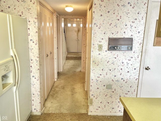 hall with light carpet and a textured ceiling