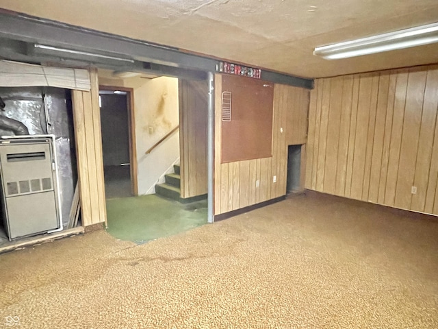 basement with carpet flooring, heating unit, and wood walls