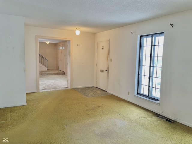 carpeted empty room with a healthy amount of sunlight and a textured ceiling