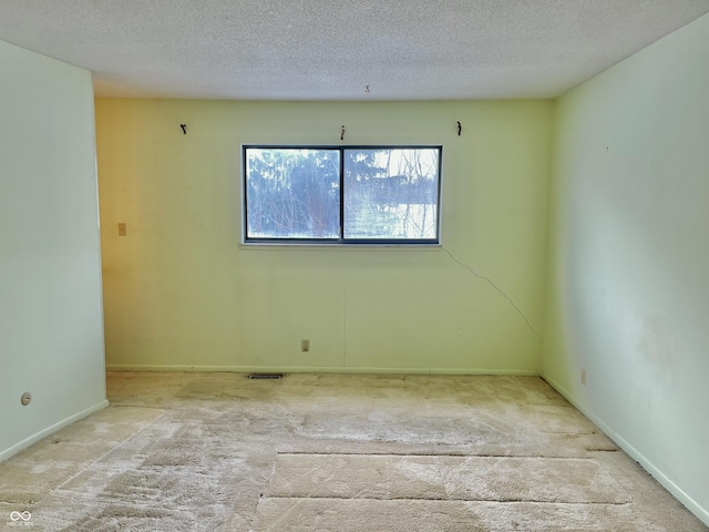 carpeted empty room with a textured ceiling