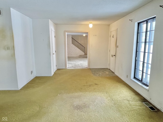 carpeted empty room featuring a wealth of natural light and a textured ceiling