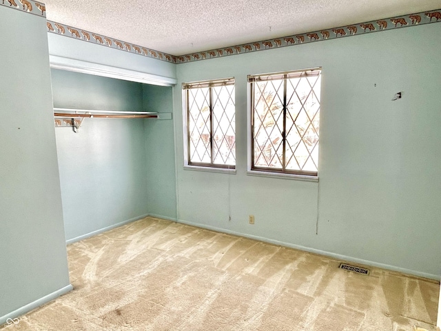 unfurnished bedroom with light colored carpet, a closet, and a textured ceiling