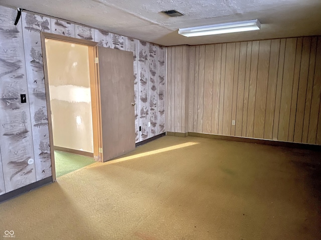 empty room with a textured ceiling and wood walls