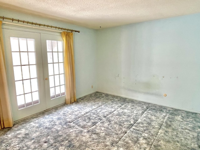 carpeted empty room featuring french doors, a healthy amount of sunlight, and a textured ceiling