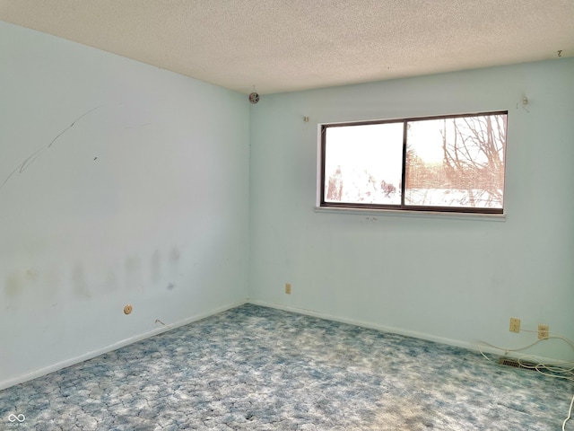 carpeted empty room featuring a textured ceiling