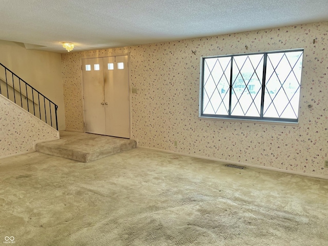 carpeted entrance foyer with a textured ceiling