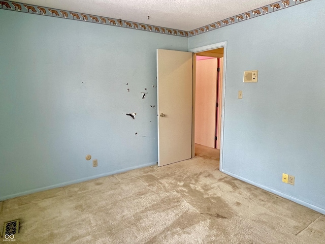 empty room with light carpet and a textured ceiling