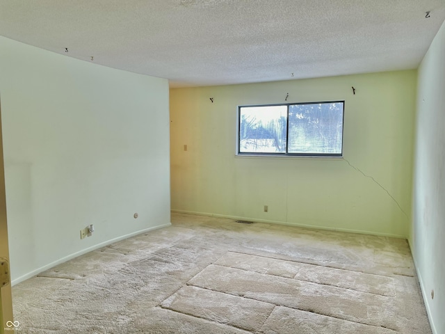 spare room featuring light carpet and a textured ceiling