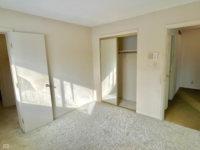 unfurnished bedroom with light colored carpet and a closet