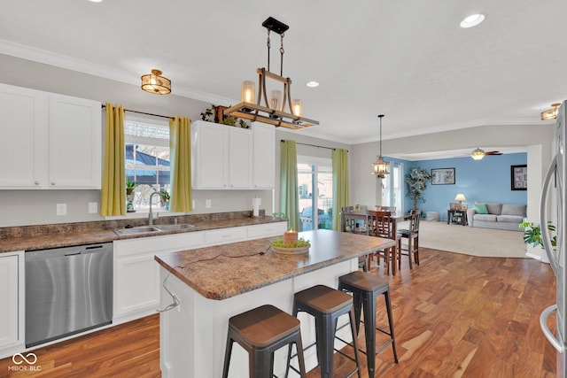 kitchen with a center island, a breakfast bar, sink, white cabinetry, and appliances with stainless steel finishes