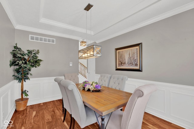 dining space with a notable chandelier, crown molding, and light hardwood / wood-style flooring