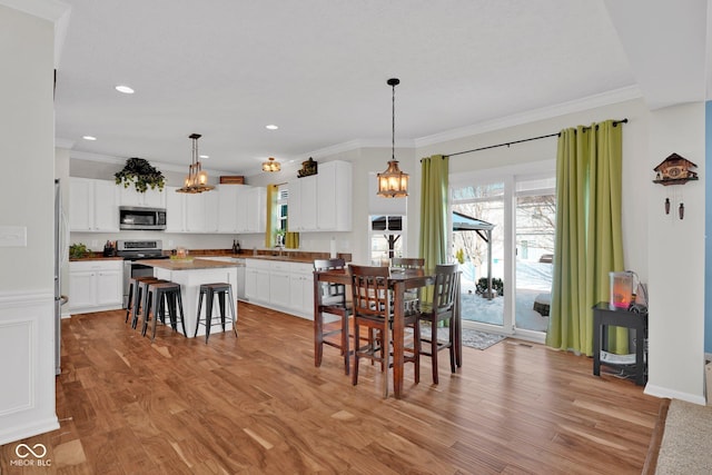 dining space featuring sink, ornamental molding, and light hardwood / wood-style flooring