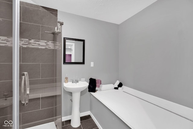 bathroom featuring tile patterned flooring, a textured ceiling, and a tile shower