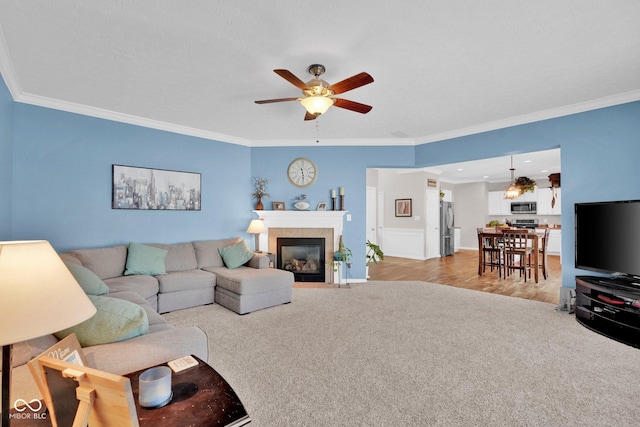 living room with ceiling fan, light carpet, and ornamental molding