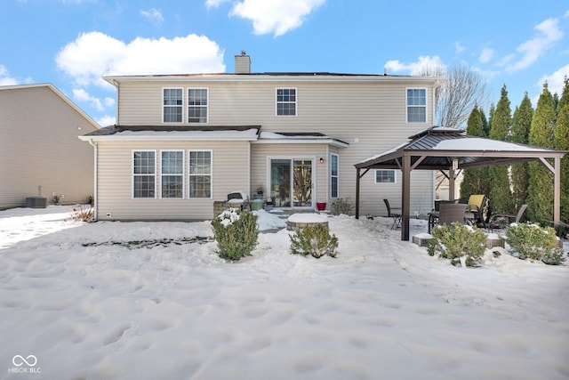 snow covered back of property with central AC unit and a gazebo