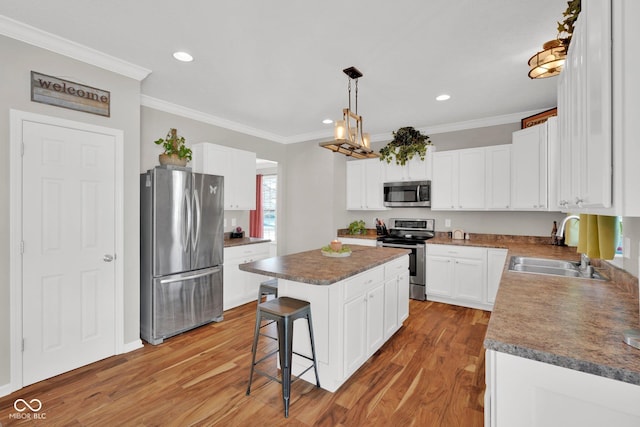 kitchen featuring a breakfast bar area, appliances with stainless steel finishes, a kitchen island, white cabinets, and sink